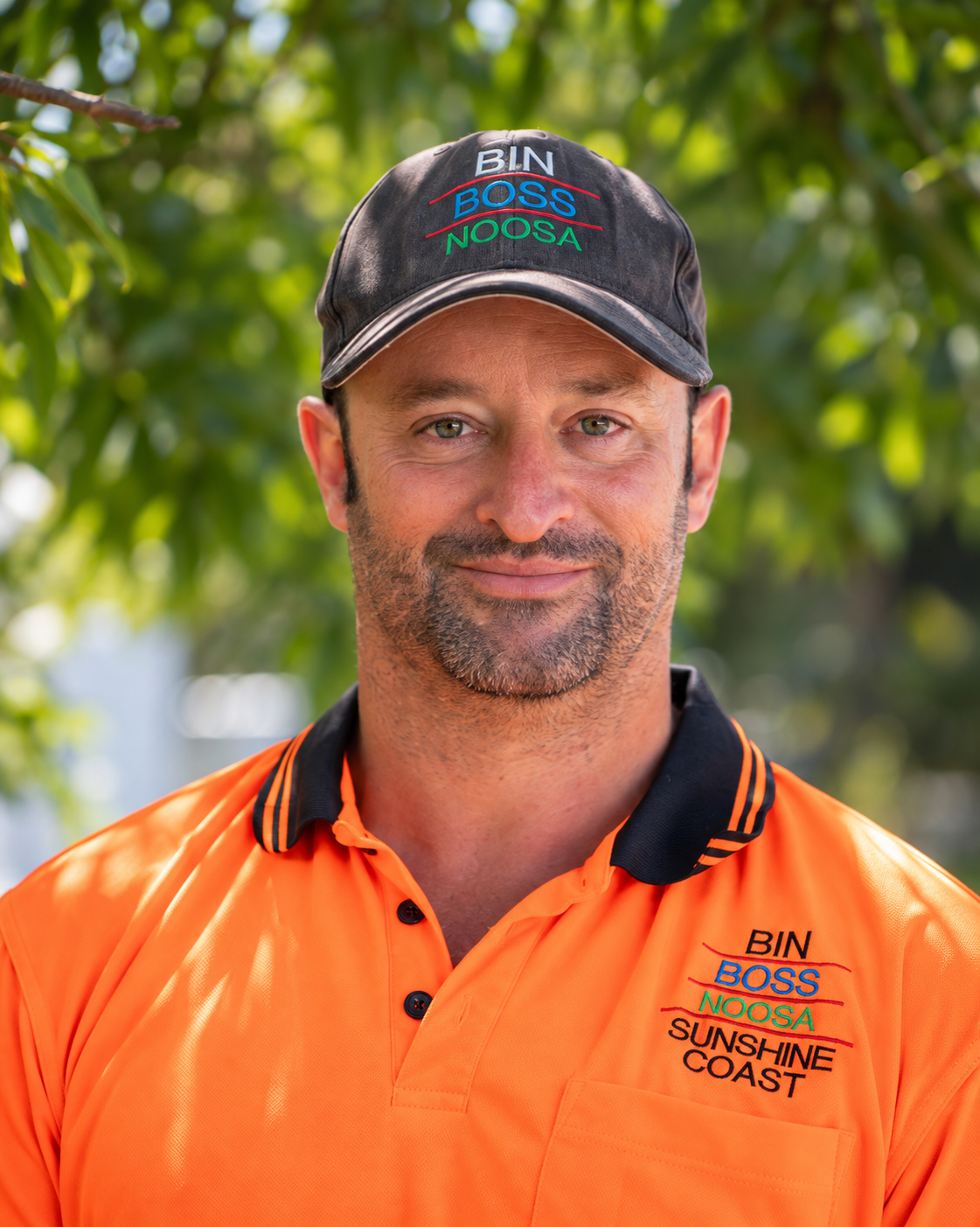 David, the local owner of Bin Boss Noosa Sunshine Coast, smiling in his branded cap and hi-vis shirt